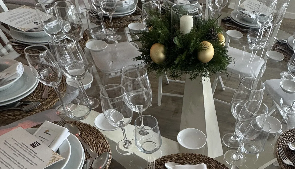 Mesa redonda de vidro com centro de pinheiro, bolas douradas e vela, no jantar de Natal da Samsic